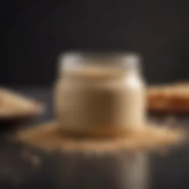 A jar of creamy tahini with sesame seeds scattered around.